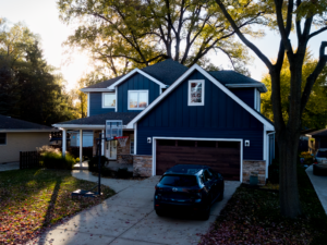 Modern home exterior with dark blue siding, stone accents, and balanced rooflines, showcasing cohesive design, curb appeal, and well-planned renovation elements.