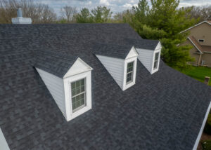 Close-up of asphalt shingle roof with dormer windows, showing uniform color and proper matching for consistent roofing appearance after repairs.