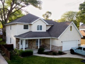 Front view of a renovated home with new roof, updated siding, stone accents, and landscaped yard enhancing curb appeal and exterior appearance.