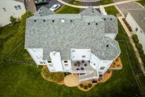 Aerial view of a modern home with new shingle roofing, backyard deck, landscaped lawn, and clean exterior showcasing enhanced curb appeal and design.