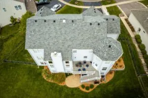 Aerial view of a modern home with new shingle roofing, backyard deck, landscaped lawn, and clean exterior showcasing enhanced curb appeal and design.